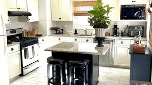 A modern kitchen with white cabinetry, a central island with stools, a stove, and a microwave. - Summer Special June 20-27, July 6-11, July 25-Aug 1. Sleeps 12 and pet friendly  (Lavallette)