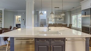 Una cocina amplia con una isla grande, electrodomésticos de acero inoxidable e iluminación colgante.