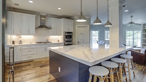 Una cocina moderna con armarios blancos, una isla grande y taburetes de bar.