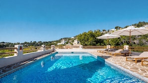 A swimming pool with tiled edges, lounge chairs, and umbrellas, surrounded by a wooden deck and overlooking a hillside. - Villa 'Robis Moraira' with Sea View, Wi-Fi and Air Conditioning (Benissa)