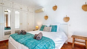 A bedroom with a bed, a wardrobe, a bench, and wall decorations. - Villa 'Robis Moraira' with Sea View, Wi-Fi and Air Conditioning (Benissa)