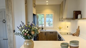 A modern kitchen with a central island, wooden cabinets, a vase of flowers, and a window with a view. - Villa 'Robis Moraira' with Sea View, Wi-Fi and Air Conditioning (Benissa)