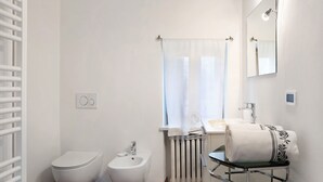 Un baño con inodoro, bidé, lavamanos y perchero para toallas.