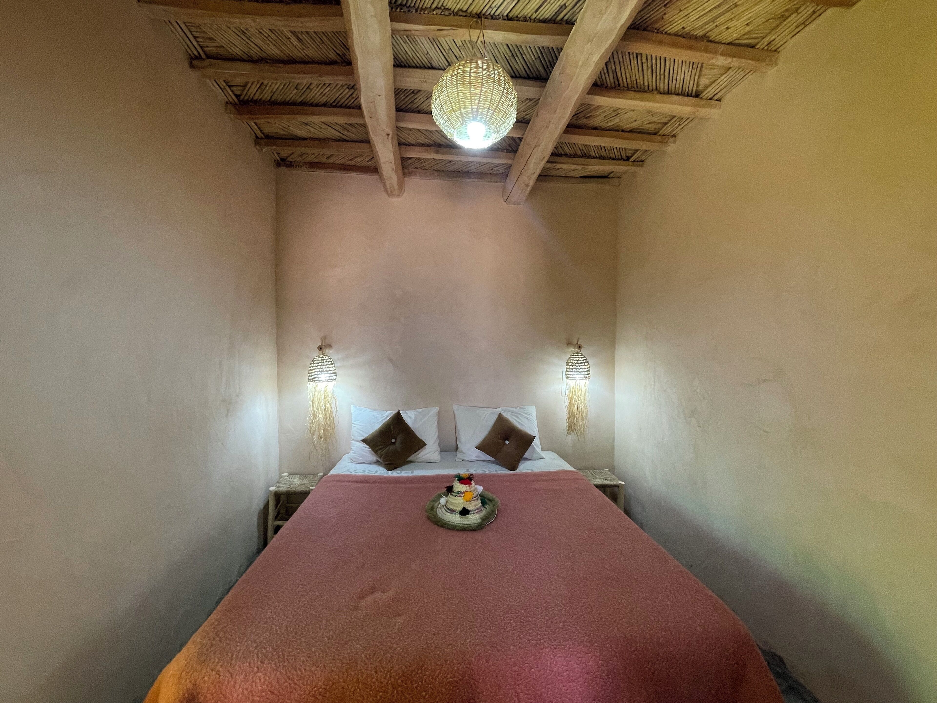 A room with a bed, two wall-mounted lamps, and a hanging light fixture.