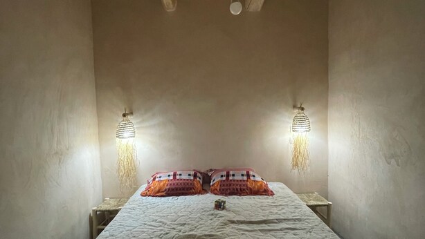 A room with a bed, two wall-mounted lamps, and a hanging light fixture. - Maroc des Merveilles - Chez l'habitant (Ait Sedrate Sahl El Gharbia)