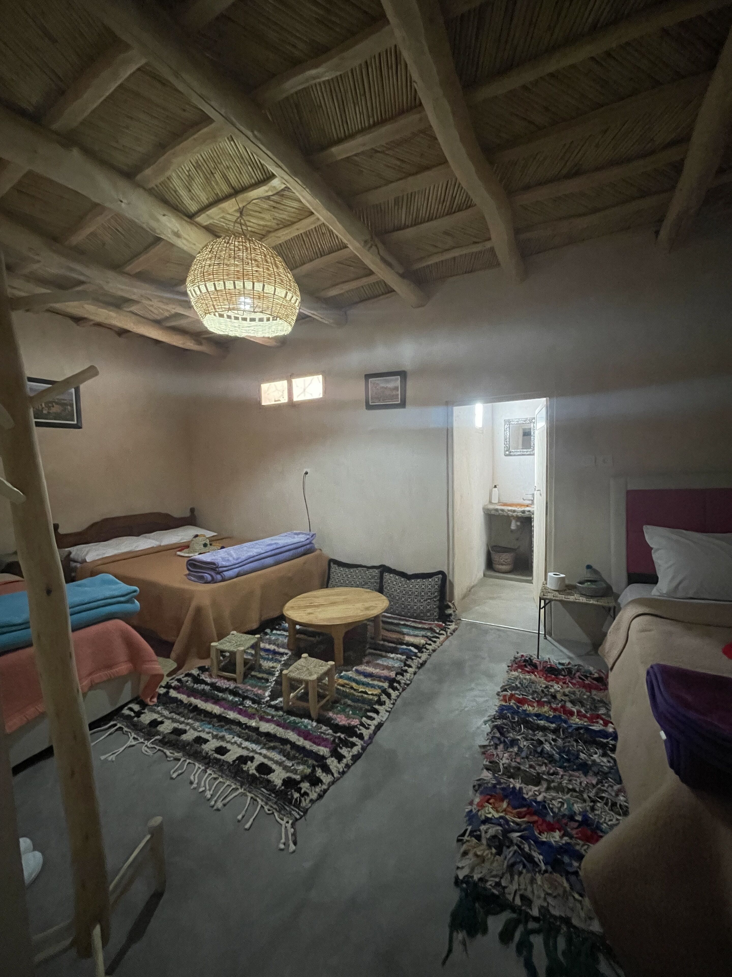 Una habitación acogedora con una cama, una mesita, una silla y una lámpara colgante.