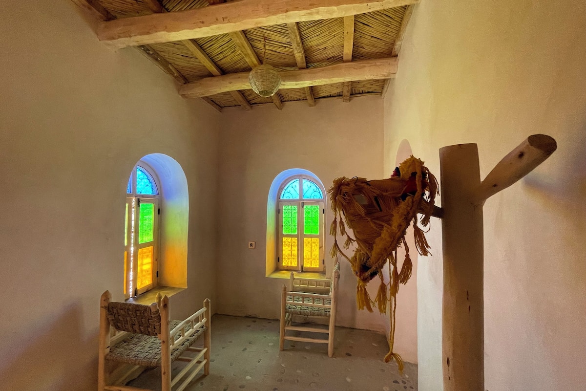 Ein Zimmer mit zwei Bogenfenstern, Holzbalken an der Decke und einer Leiter.