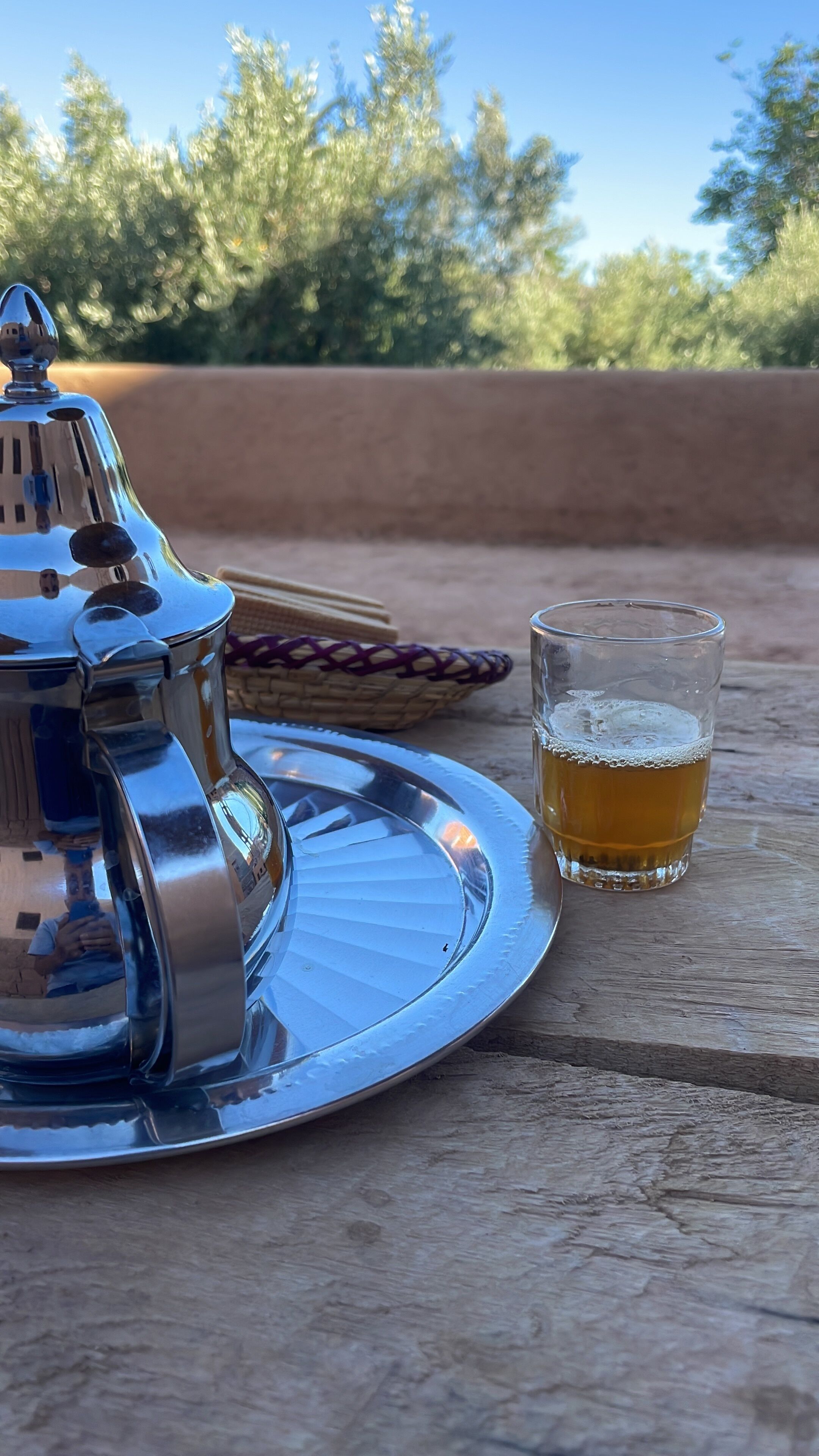 A metal tray with a glass of beer and a metal container on a wooden surface.