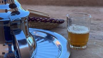 A metal tray with a glass of beer and a metal container on a wooden surface.