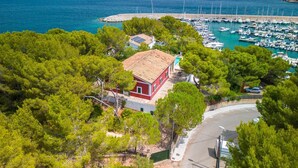 A coastal property with a red building, a marina with boats, and a view of the sea.