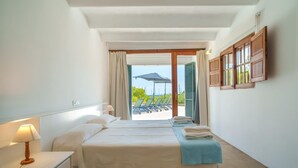 A hotel room with a bed, a bedside table with a lamp, a window with curtains, and a view of the outside.