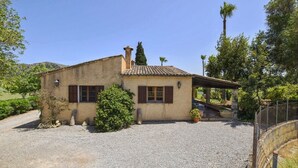 Un bâtiment de style rustique, avec un toit en tuiles, une allée en gravier et un mur en pierre.