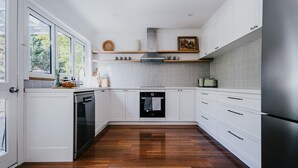 Eine moderne Küche mit weißen Schränken, einem eingebauten Backofen und einem Edelstahl-Kühlschrank.