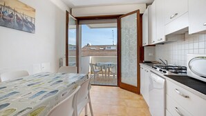 A compact kitchen with a dining area, a view to the outside, and a small balcony. - Apartment 'Residence Papaya A202' with Shared Pool and Private Terrace (Jesolo)