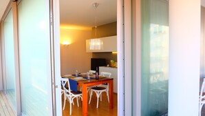 A dining area with a wooden table, white chairs, and a hanging light fixture. - Apartment 'Residence Shine 06' with Private Terrace and Air Conditioning (Jesolo)