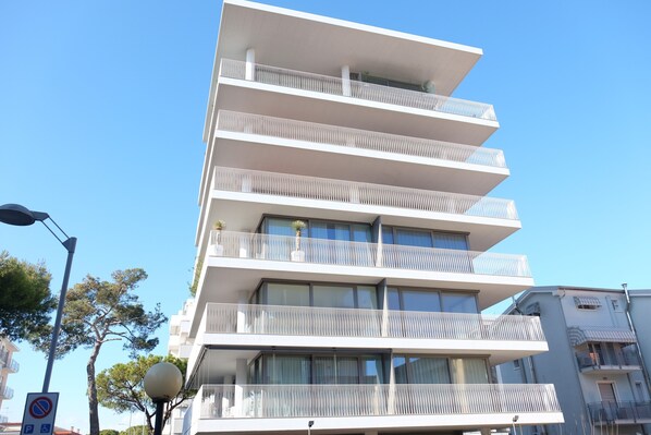 Un immeuble à plusieurs étages, doté de balcons, de grandes fenêtres et surplombant un ciel dégagé.