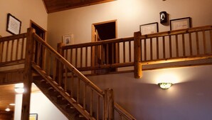 A wooden staircase with a handrail, leading to an upper level.