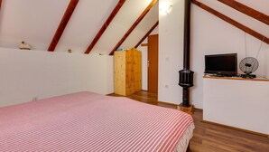 A bedroom with a bed, wooden wardrobe, and a TV on a shelf. - Lovely home in Veliki Grdevac with WiFi (Veliki Grdevac)