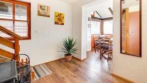 A hallway with wooden flooring, a potted plant, a striped rug, and a dining area with wooden chairs and a table. - Lovely home in Veliki Grdevac with WiFi (Veliki Grdevac)