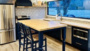 Una cocina moderna con una isla de madera, electrodomésticos de acero inoxidable y un amplio ventanal con vistas al agua.