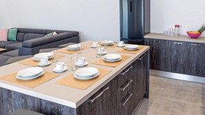 A modern kitchen with a central island, dark wooden cabinets, and a grey sofa in the background. - Amazing home in Kraljevica (Kraljevica)