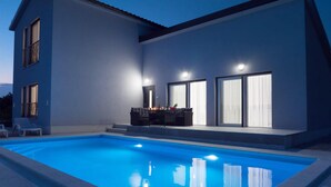 A modern house with a swimming pool, a dining area with a table and chairs, and large windows. - Amazing home in Kraljevica (Kraljevica)