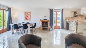 Ein modernes Wohnzimmer mit Kamin, Essbereich und großen Fenstern.