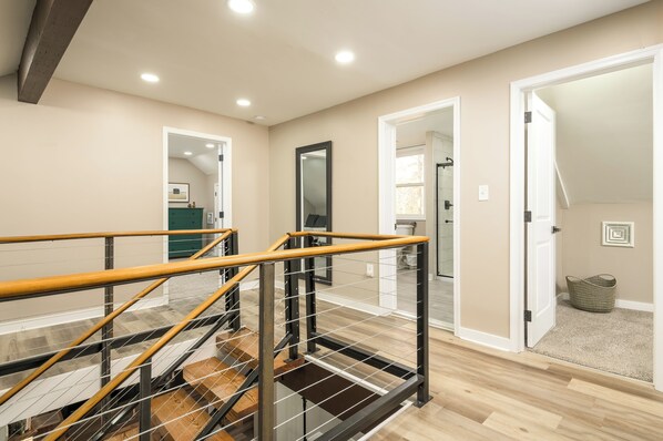 Un interior moderno con una escalera de madera, paredes color beige y un baño a la vista.