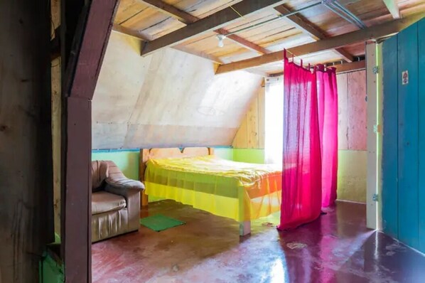 A room with a bed, a chair, and a door.