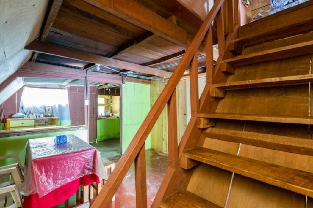 Una escala de fusta que condueix a un nivell superior amb un taulell cobert per un drap vermell.