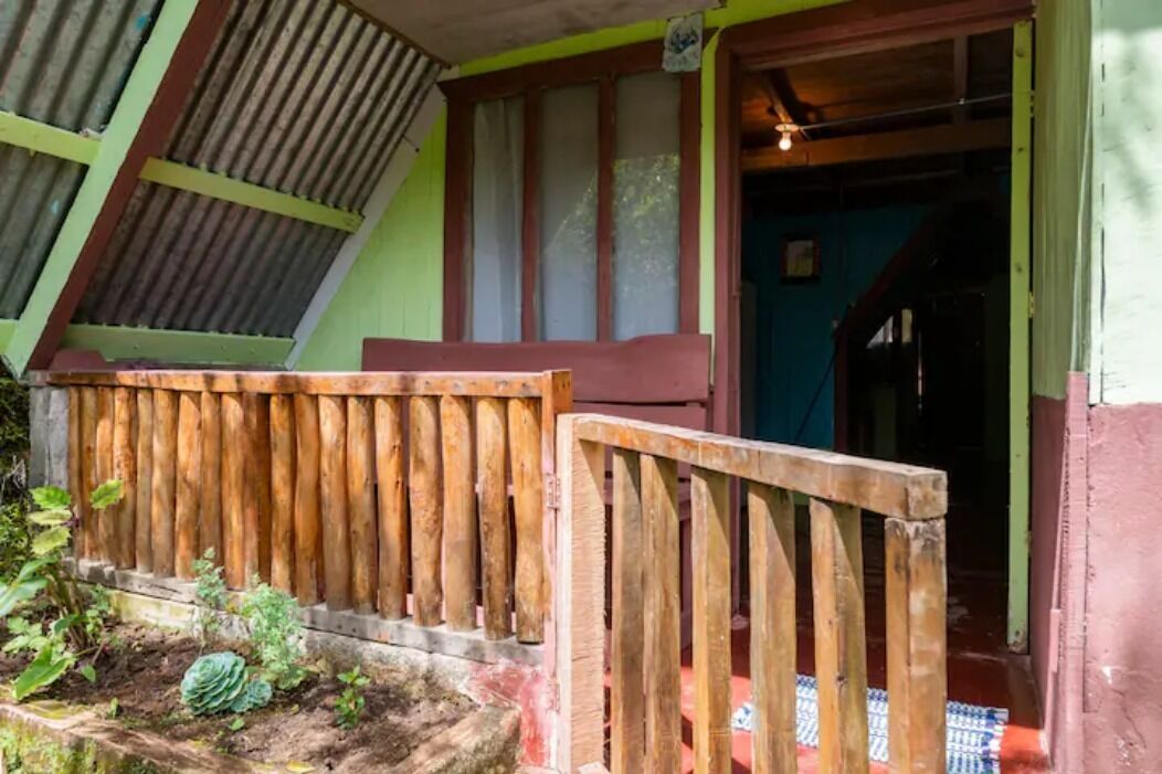 Une porte en bois qui mène à un porche à l’extérieur peint en vert et en rouge.