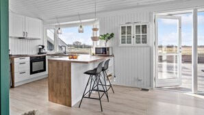 Een moderne keuken met een houten keukeneiland, witte kasten en een groot raam met uitzicht op de omgeving.