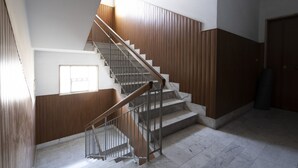 Una escalera con paneles de madera y barandales de metal que conduce a una plataforma con ventana.