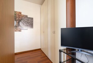 Ein Zimmer mit einem Flachbildfernseher auf einem Glaskonzol, Holzboden und einer Wand mit drei gerahmten Bildern.