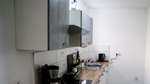 A compact kitchen with a wooden countertop, a built-in stove, a coffee maker, and a kettle.