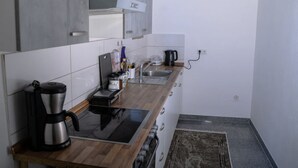 A compact kitchen with a coffee maker, a kettle, and a toaster on the counter.
