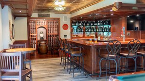 A bar area with wooden bar stools, a wine cellar sign, and a variety of bottles on shelves. - Rare Super Host - Arcade w/ 5 Kings, Hot Tub, Pub (Inver Grove Heights)