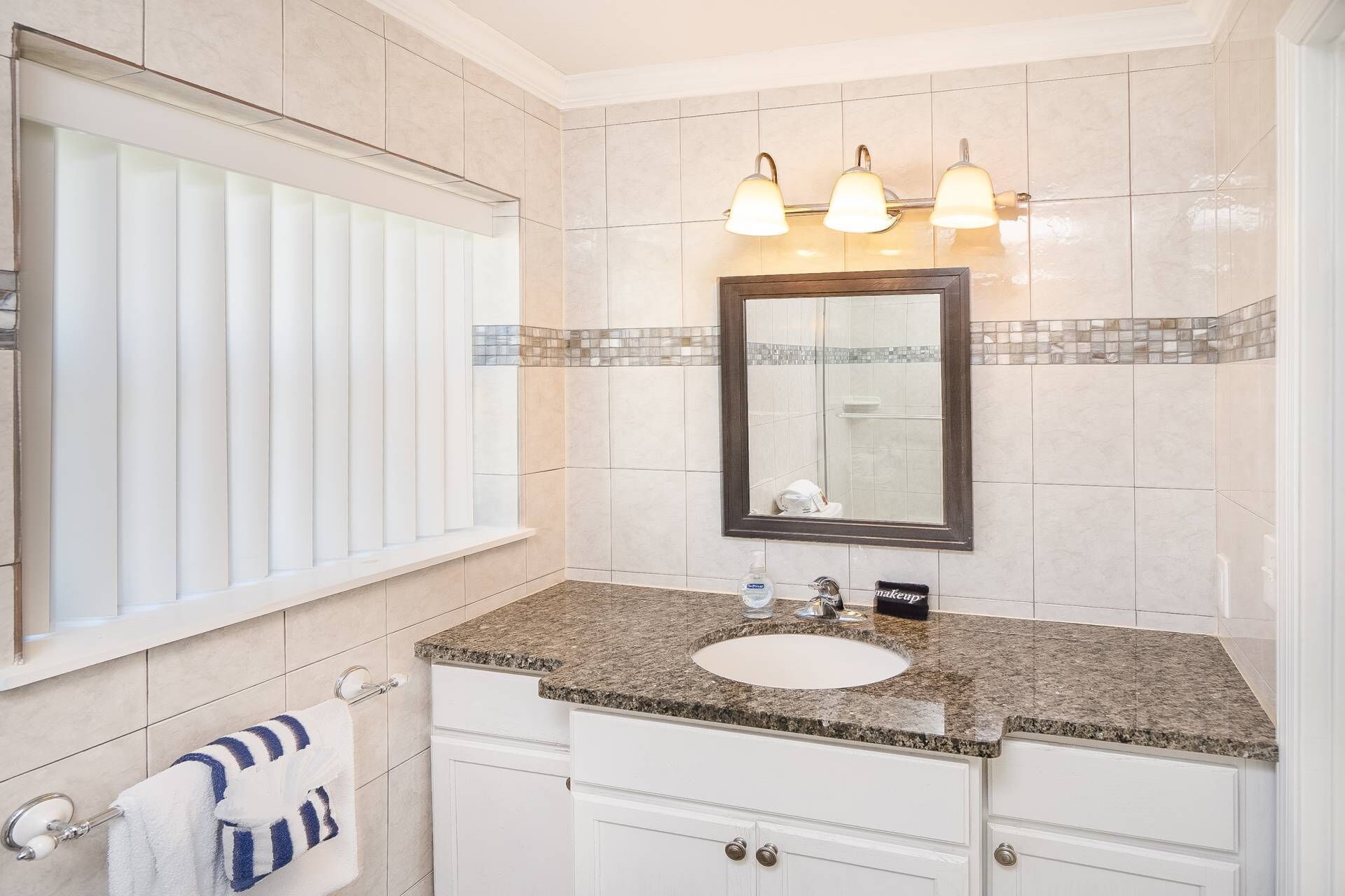 A bathroom with a large mirror, a sink, and a vanity with drawers.