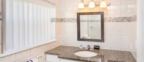 A bathroom with a large mirror, a sink, and a vanity with drawers.