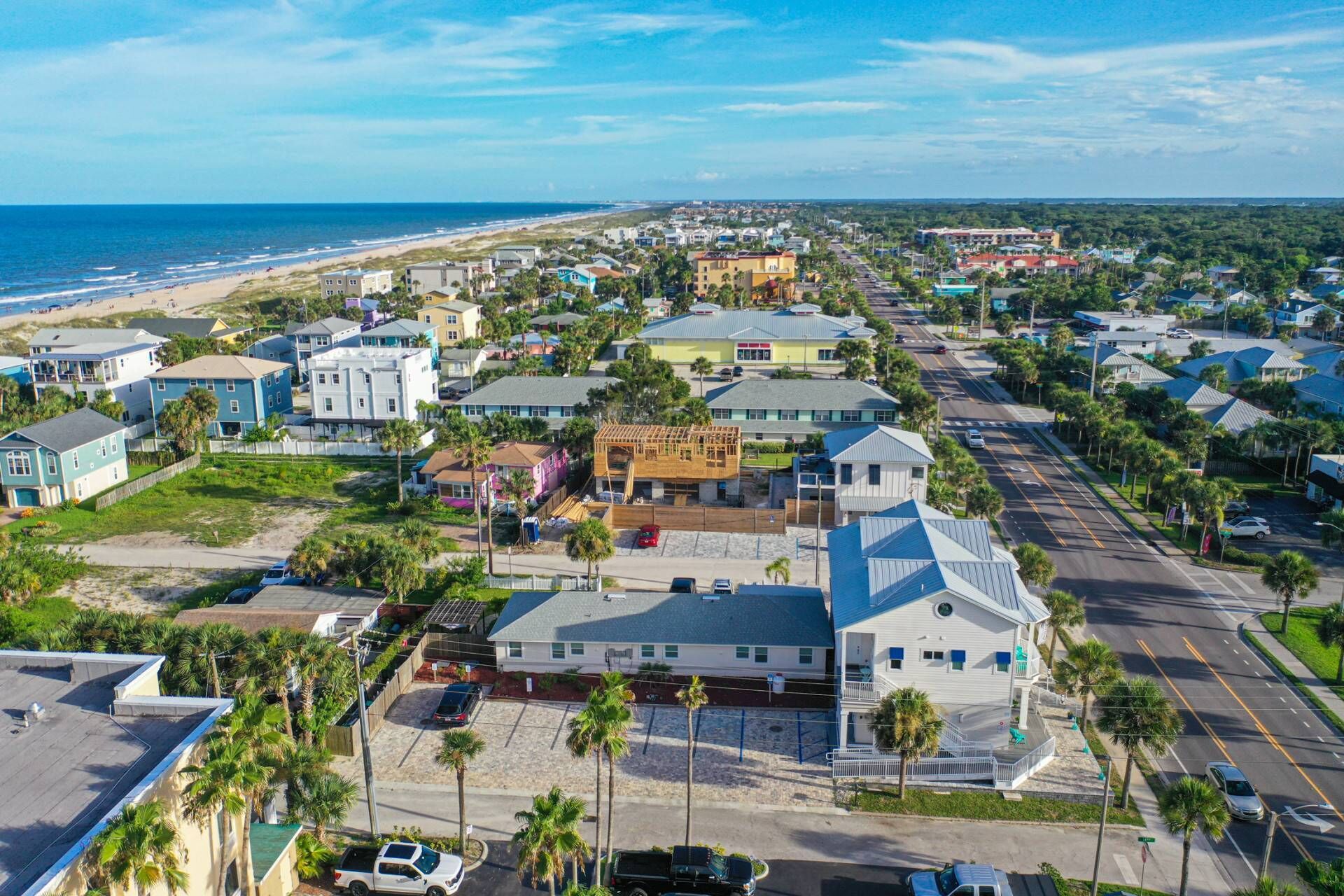 A coastal residential area with houses, a beach, and a clear sky.