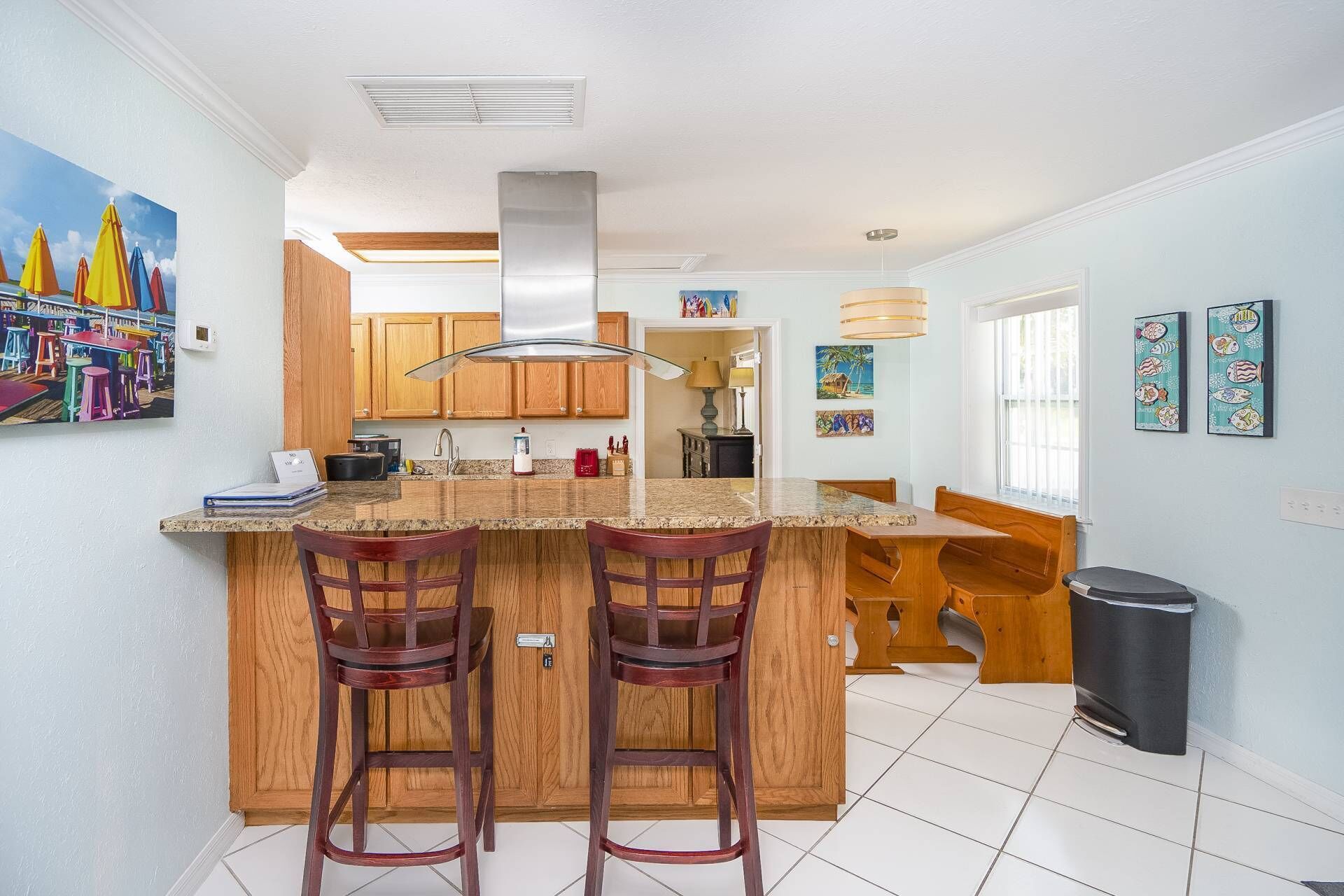 A kitchen with a central island, wooden cabinets, and a stainless steel range hood.