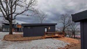 Un bâtiment moderne à l’extérieur sombre, avec un banc en bois et un sol recouvert de gravier.
