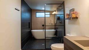 Une salle de bain moderne avec une baignoire sur pieds, des toilettes et un espace douche.