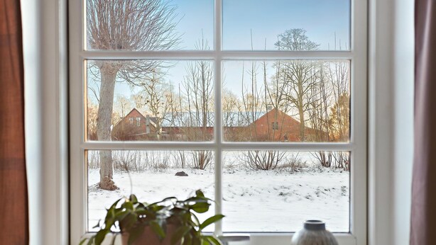 Una ventana con vista a un paisaje nevado y un edificio de ladrillo.