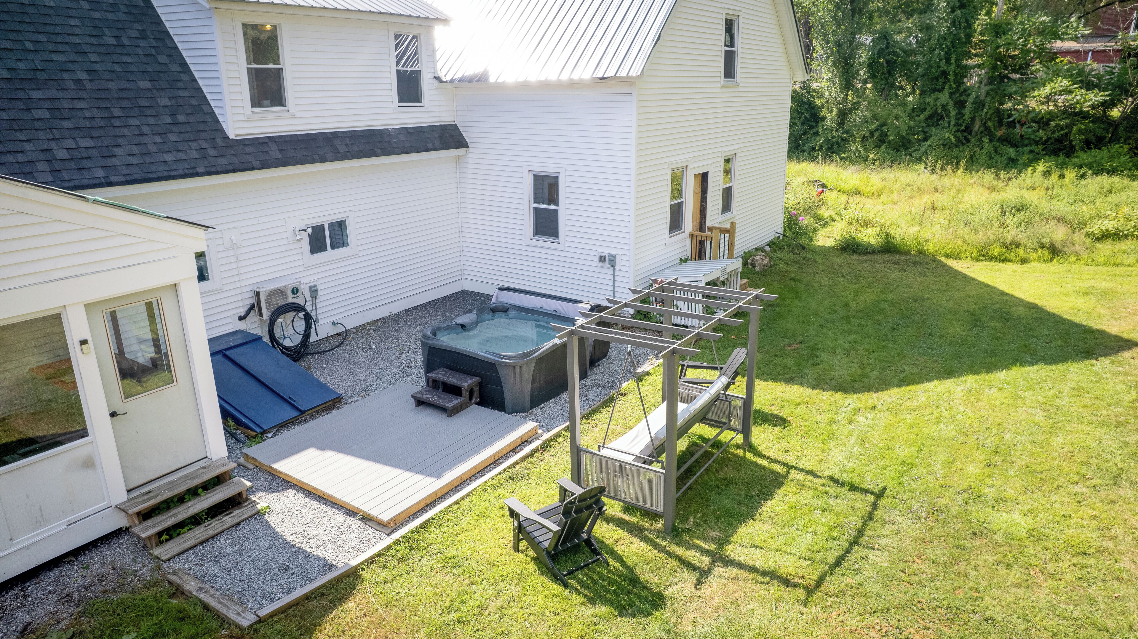 Une maison dotée d’un jacuzzi, d’une terrasse et d’un espace salon extérieur.