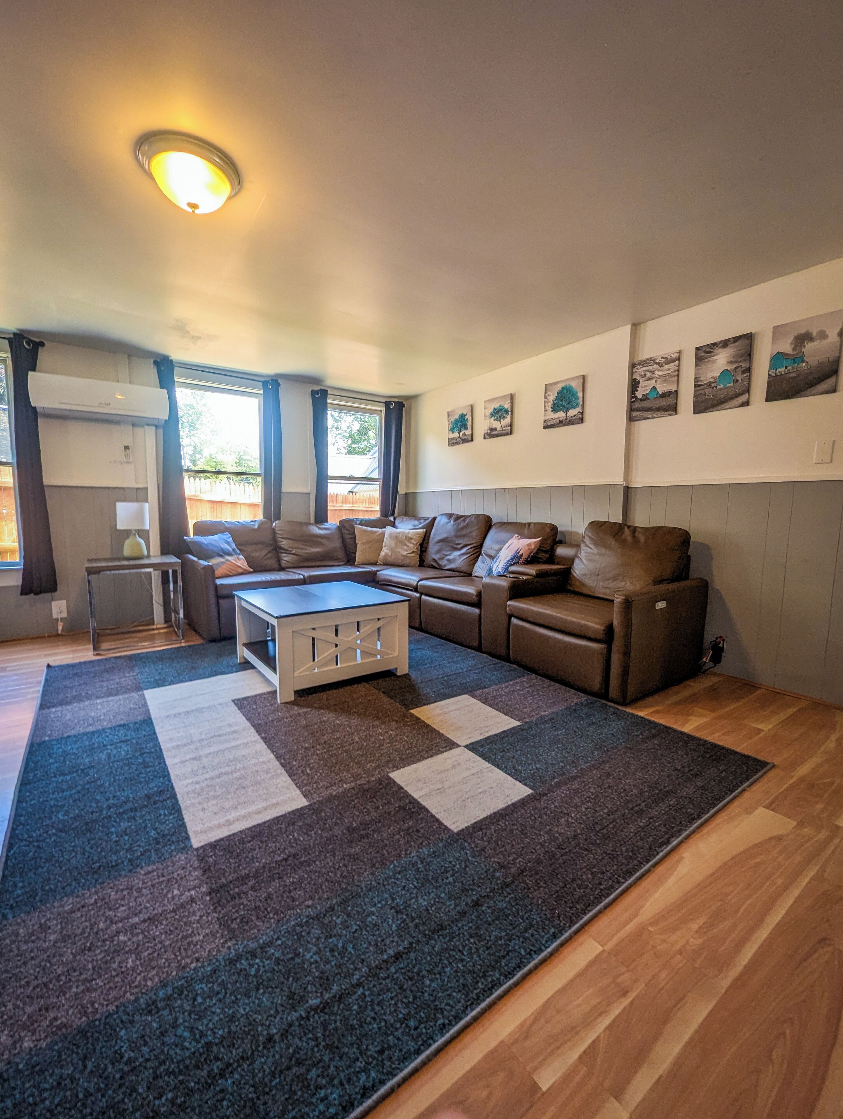 Ein gemütliches Wohnzimmer mit einem Ecksofa, einem Couchtisch und einem gemusterten Teppich.
