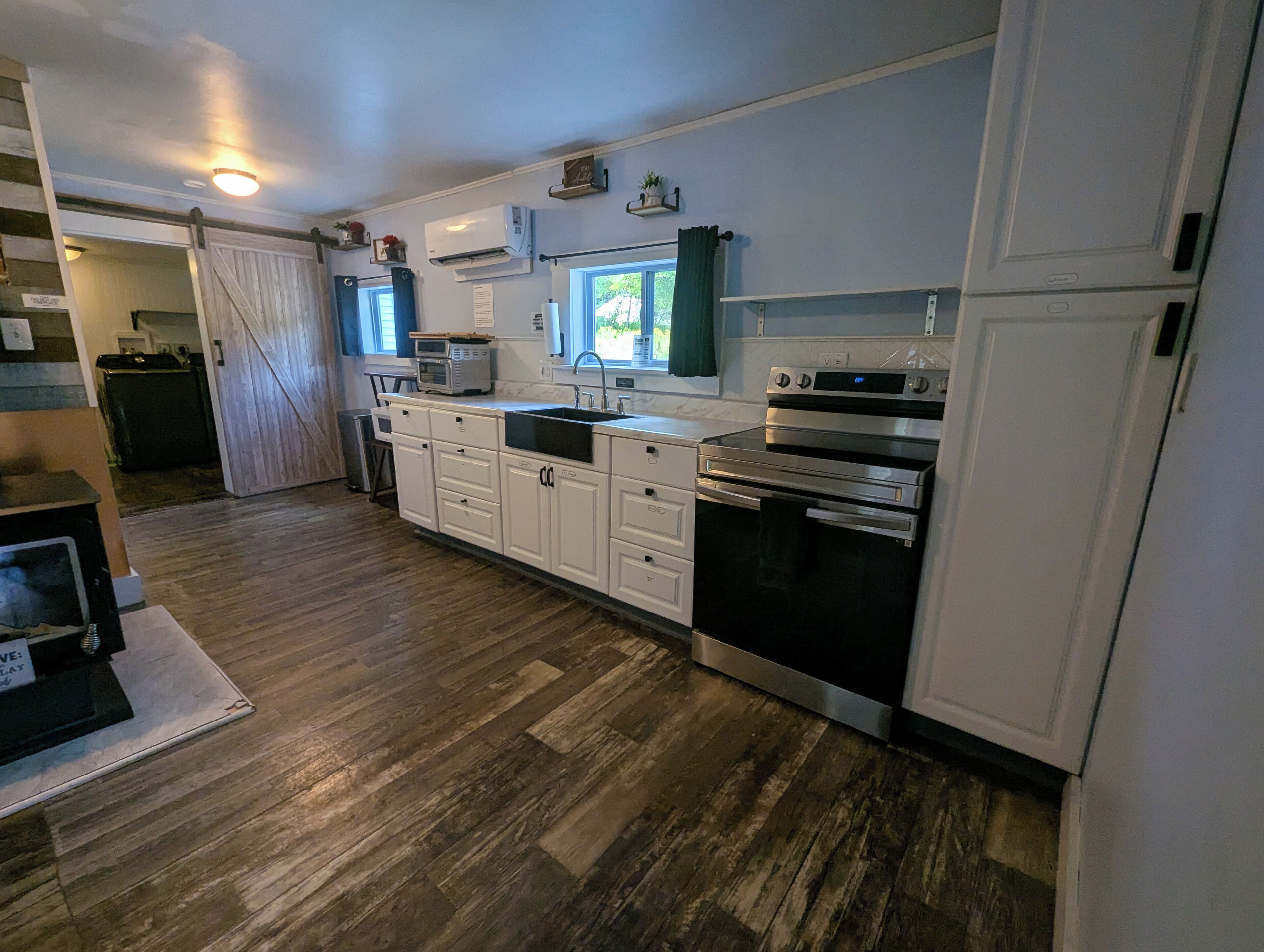 A modern kitchen with white cabinets, a stainless steel oven, and a microwave.