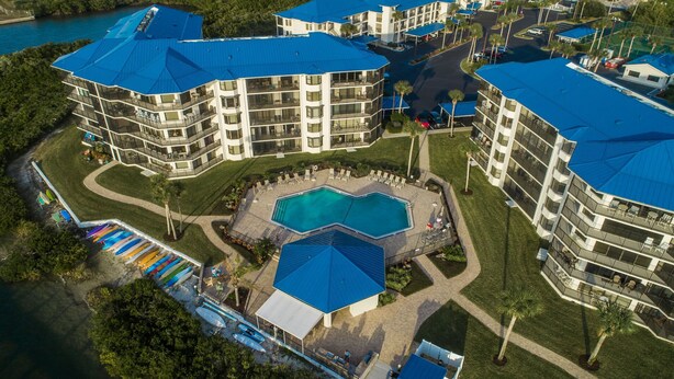 A multi-story hotel with a central pool area surrounded by balconies and a parking lot. - Inlet Marina Villas #524, Nestled between the River & Ocean (New Smyrna Beach)