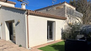 Una casa con techo de tejas, un pequeño jardín y un camino de entrada pavimentado.