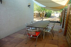 A patio with a table and chairs, a lamp, and a wooden fence. - Lovely Detached Villa with large garden Rochelongue Cap d'Agde (LE CAP D AGDE)
